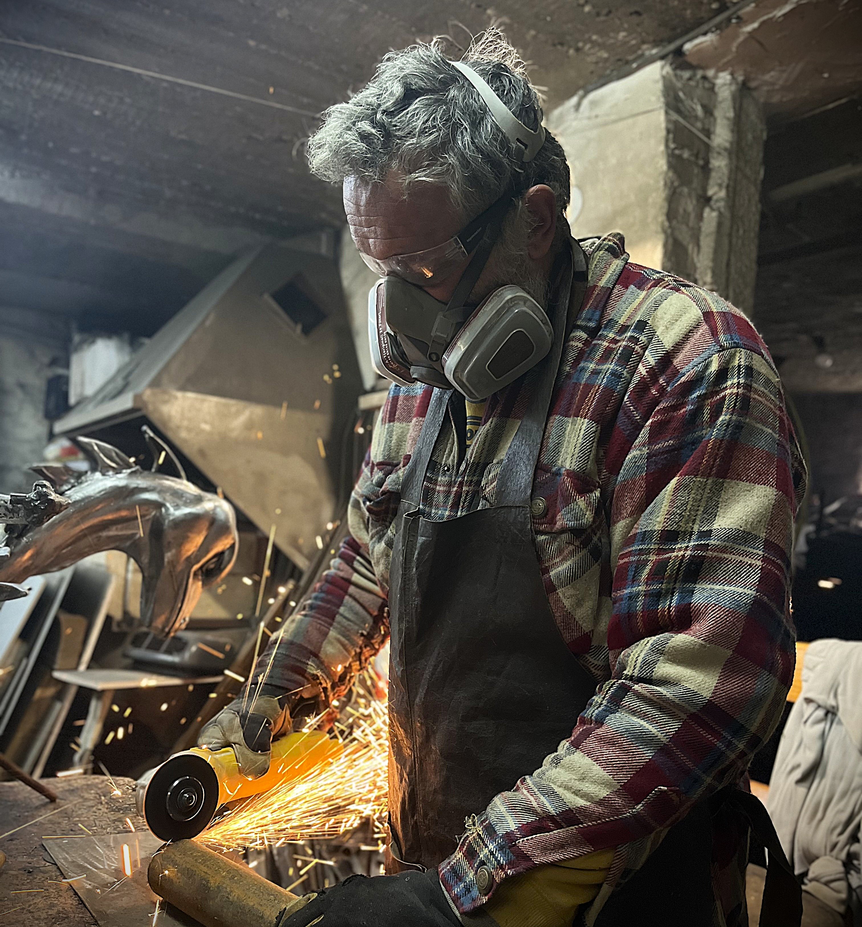 The artist grinding metal in the workshop